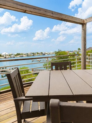 A wooden deck with a table and chairs overlooking a marina and water. - Needle Rush Point E34, Beach Access, 2 Pools, Riverfront, Private Beach (Pensacola)