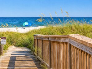 Ein hölzerner Steg führt zu einem Strand, ein Schild kennzeichnet einen privaten Strandabschnitt.