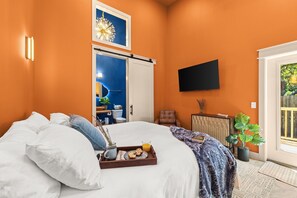 A hotel room with a bed, a tray with breakfast, a TV, a door leading to a bathroom, and a window with a view. - 3 King Beds*Resort Pool*Private Beach Access (Panama City Beach)