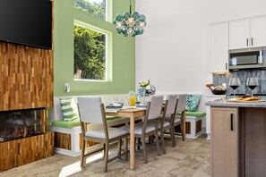 Eine moderne Küche mit Essbereich, einem eingebauten Kamin und einem großen Fenster.