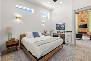 Ein modernes Schlafzimmer mit Bett, Nachttisch, Lampe und Kunstwerk.