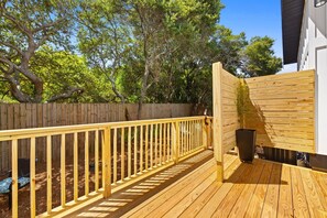 Eine Holzterrasse mit Geländer, ein Holzzaun und ein Blumentopf.