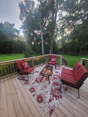 Eine Terrasse mit einem rot-weißen Teppich, zwei roten Stühlen mit schwarzen Gestellen und einem kleinen Tisch.
