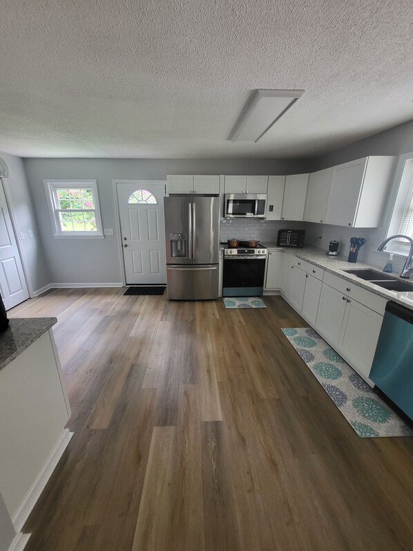 A kitchen with a refrigerator, microwave, oven, and sink.