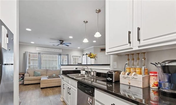 A modern kitchen with white cabinets, a coffee bar, and a dining area with a sofa. - Gameday and weekend oasis! (Tuscaloosa)