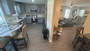 A modern kitchen with stainless steel appliances, a dining area with a marble table, and a living room with a sofa and coffee table. - Enjoyable historic Duplex next door to Hutchins BBQ (McKinney)