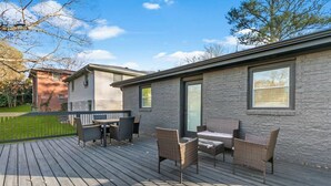 A deck with outdoor furniture, a brick building, and a clear sky. - Family-Friendly 4BR Home | Near Downtown ATL (Atlanta)