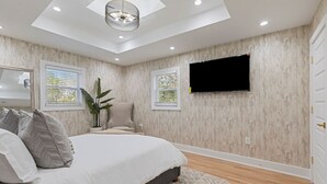 A bedroom with a bed, a chair, a TV mounted on the wall, and a skylight. - Family-Friendly 4BR Home | Near Downtown ATL (Atlanta)
