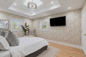 A bedroom with a bed, a chair, a TV mounted on the wall, and a skylight. - Family-Friendly 4BR Home | Near Downtown ATL (Atlanta)