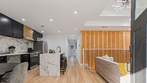 A modern kitchen with dark cabinets, a marble island, and a dining area with a gray chair. - Family-Friendly 4BR Home | Near Downtown ATL (Atlanta)