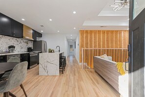 A modern kitchen with dark cabinets, a marble island, and a dining area with a gray chair. - Family-Friendly 4BR Home | Near Downtown ATL (Atlanta)