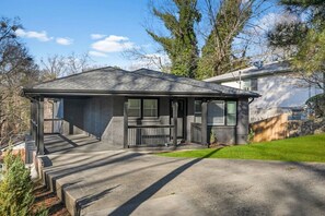 A residential house with a covered porch, a front yard, and a driveway. - Family-Friendly 4BR Home | Near Downtown ATL (Atlanta)