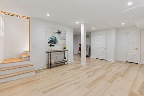 A modern interior with a staircase, a console table with decorative items, and a hallway leading to a door. - Family-Friendly 4BR Home | Near Downtown ATL (Atlanta)