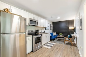 A modern kitchen with stainless steel appliances, a blue sofa, and a dark accent wall. - Charming 2BR Rear Unit Retreat Near Atlanta (Lithia Springs)