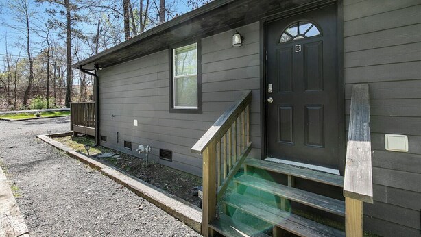 A small, single-story building with a dark front door, a small window, and a wooden staircase leading to the entrance. - Charming 2BR Rear Unit Retreat Near Atlanta (Lithia Springs)