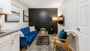 A compact living space with a sofa, armchair, coffee table, and a TV mounted on the wall. - Charming 2BR Rear Unit Retreat Near Atlanta (Lithia Springs)