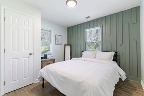 A bedroom with a bed, a dresser, a mirror, and two windows with blinds. - Charming 2BR Rear Unit Retreat Near Atlanta (Lithia Springs)