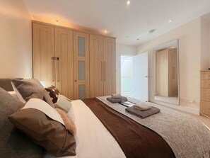 Une chambre à coucher avec un grand lit, une armoire en bois et un dressing.