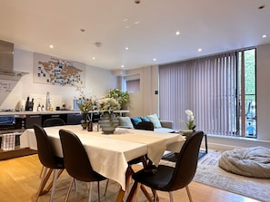 A modern dining area with a table set for four, a kitchen in the background, and a large window with blinds. - Stunning 3BRs 3F house w/AC close to Oxford (London)