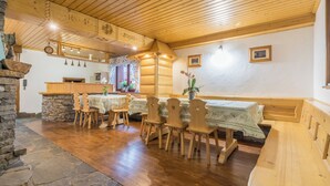 A cozy dining area with wooden furniture, stone accents, and a rustic ceiling. - Fantastic 9-bedroom house in Zakopane for your perfect getaway (Zakopane)