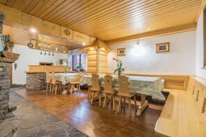 Ein gemütlicher Essbereich mit Holzmöbeln, Steinverzierungen und einer rustikalen Decke.