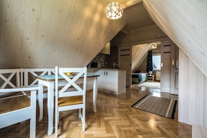A modern loft with a dining area, kitchen, and a staircase leading to an upper level. - Fantastic 9-bedroom house in Zakopane for your perfect getaway (Zakopane)