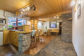 A kitchen with a stone island, wooden cabinets, and a dining area with a stone wall.