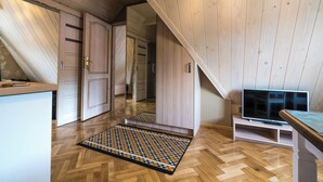 A room with wooden walls, a herringbone floor, a television, and a door leading to another room. - Fantastic 9-bedroom house in Zakopane for your perfect getaway (Zakopane)