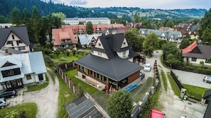 A residential area with houses, a large building with a sloped roof, and a paved driveway. - Fantastic 9-bedroom house in Zakopane for your perfect getaway (Zakopane)