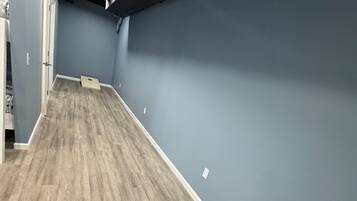 A room with a wooden floor, a table with a cushion, and a blue wall.