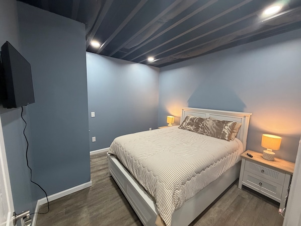 A bedroom with a bed, nightstands, a lamp, and a TV mounted on the wall. - Cute and Convenient Cabin located close to Dale Hollow Lake-Cabin#4 (Burkesville)
