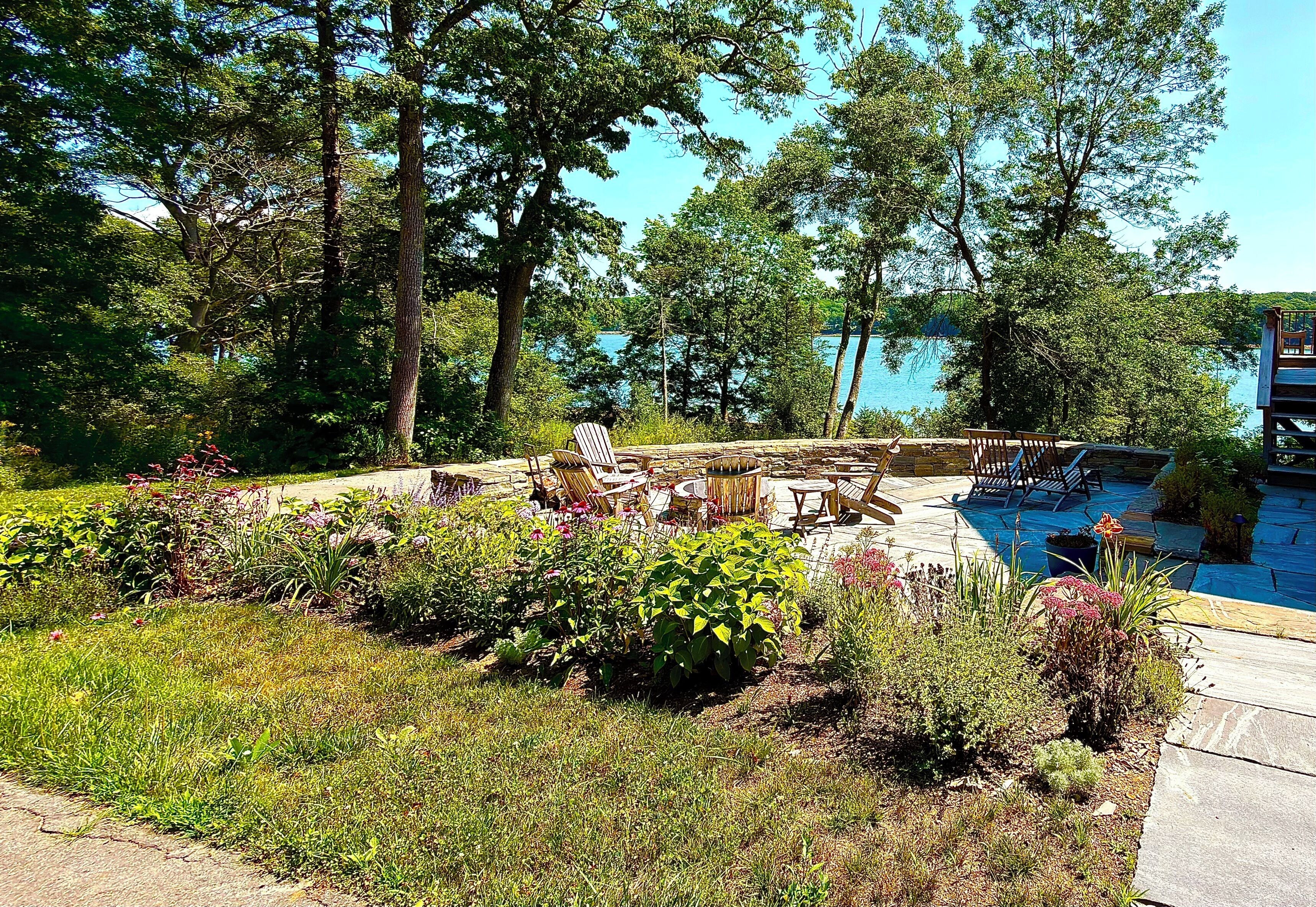 Un espace aménagé au bord de la piscine, avec des chaises longues et une petite table, le tout entouré d’une végétation luxuriante et d’arbres.