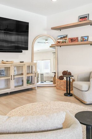 A modern living room with a flat-screen TV, a sofa, a coffee table, and a fireplace. - Mohican Escape | Stylish Backyard Retreat (Lake Havasu City)