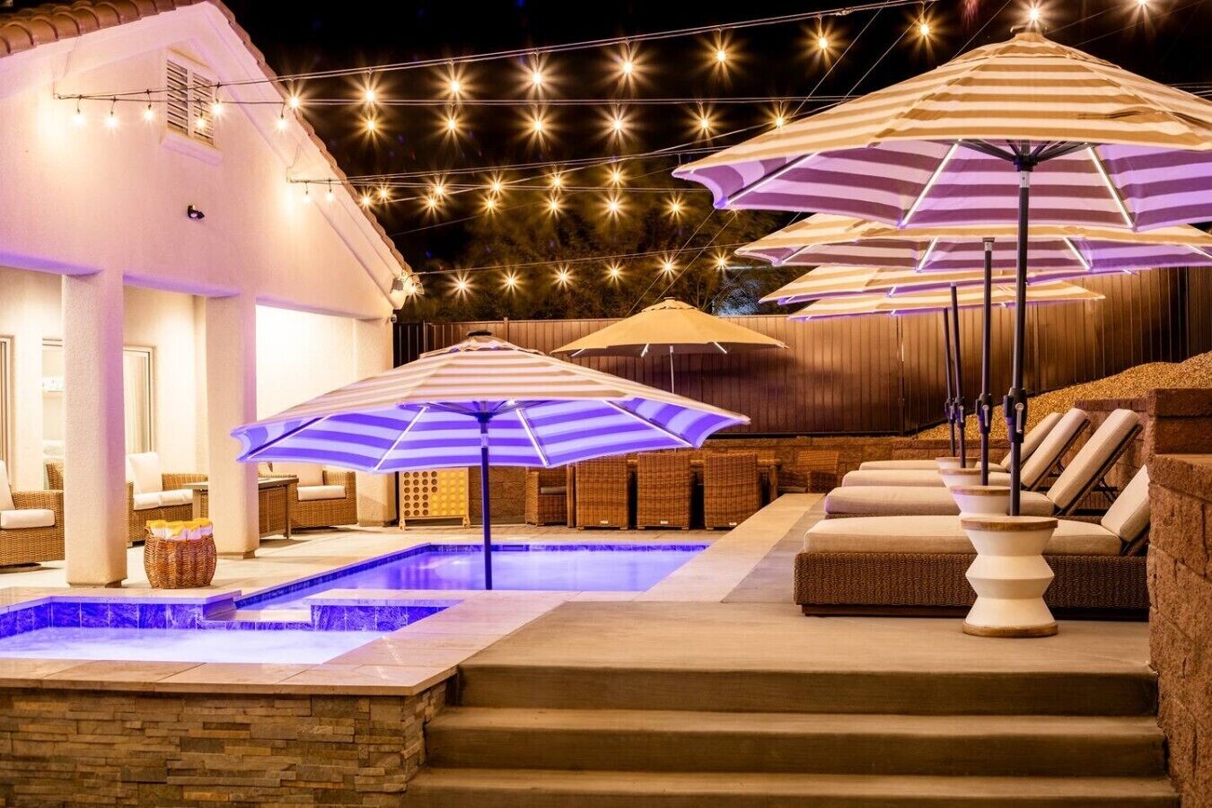 Zona de piscina con múltiples sombrillas, una alberca y mobiliario exterior.