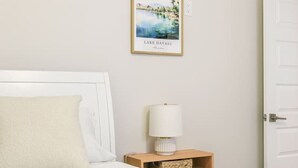 Hotelkamer met een bed, nachtkastje met lamp, lijst met foto van Lake Havasu en een witte deur.