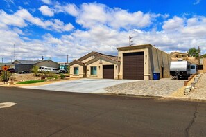 A residential area with a house featuring a garage, a driveway, and a small garden. - Mohican Escape | Stylish Backyard Retreat (Lake Havasu City)
