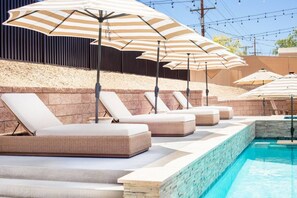Un espace aménagé au bord de la piscine, avec des chaises longues et des parasols à rayures.