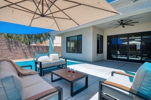 Eine moderne Außenpatio mit Pool, Sitzbereich und Sonnenschirm.