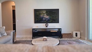 Ein Wohnzimmer mit einer Couch, einem Couchtisch, einer schwarzen Unterhaltungsecke und einem Bild an der Wand.