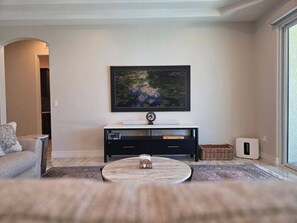 A living room with a sofa, a coffee table, a black entertainment unit, and a painting on the wall. - Luxury Retreat | Hot Tub | RV Garage | EV Charger (Lake Havasu City)