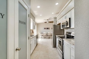 A kitchen with white cabinets, a microwave, a refrigerator, and a dining area with a table and chairs. - Pet friendly home w/ pool, spa & toiletries (Lake Havasu City)