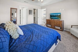 A bedroom with a large bed, a dresser, a television, and a door leading to a bathroom. - Pet friendly home w/ pool, spa & toiletries (Lake Havasu City)