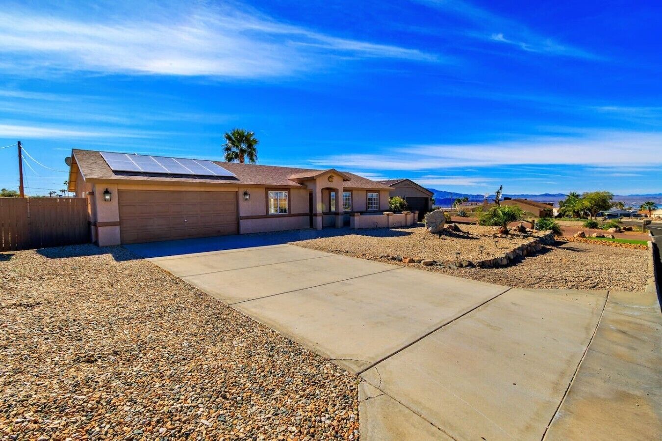A residential house with a garage, solar panels, and a clear view of the mountains in the background.