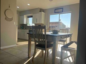 A dining area with a table and chairs, a kitchen in the background, and a sign that reads 'WELCOME'. - Pet friendly home w/ pool, spa & toiletries (Lake Havasu City)