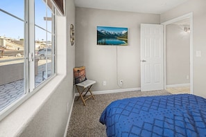 A bedroom with a bed, a chair, a painting, and a door. - Pet friendly home w/ pool, spa & toiletries (Lake Havasu City)