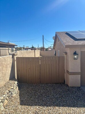 A residential property with a gated entrance, a solar panel on the roof, and a clear blue sky. - Pet friendly home w/ pool, spa & toiletries (Lake Havasu City)