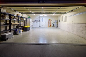 Eine saubere, gut beleuchtete Garage mit Regalen, einer Leiter und einer Waschmaschine.