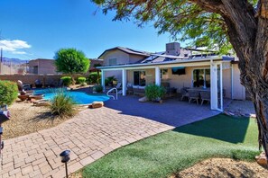 Ein Garten mit Swimmingpool, Gartenmöbeln und einer überdachten Sitzgruppe.