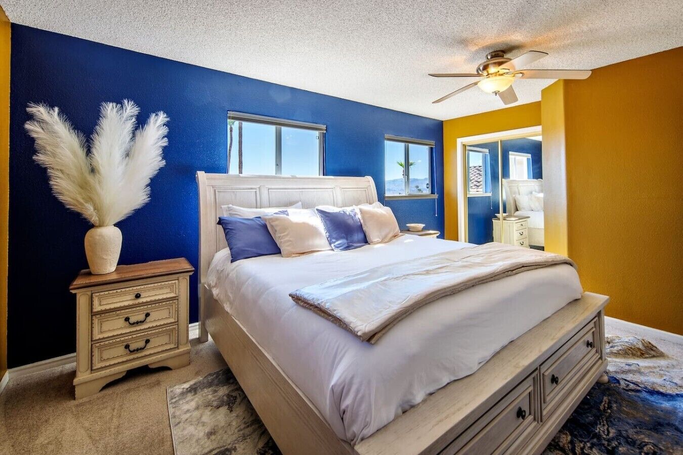 A bedroom with a bed, nightstands, a ceiling fan, and a window.