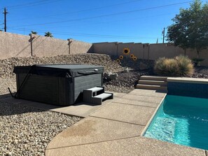 A swimming pool with a stone deck, a hot tub, and a small garden area with sunflowers. - Sleeps 12 w/ ping pong & pool table| comfort + (Lake Havasu City)